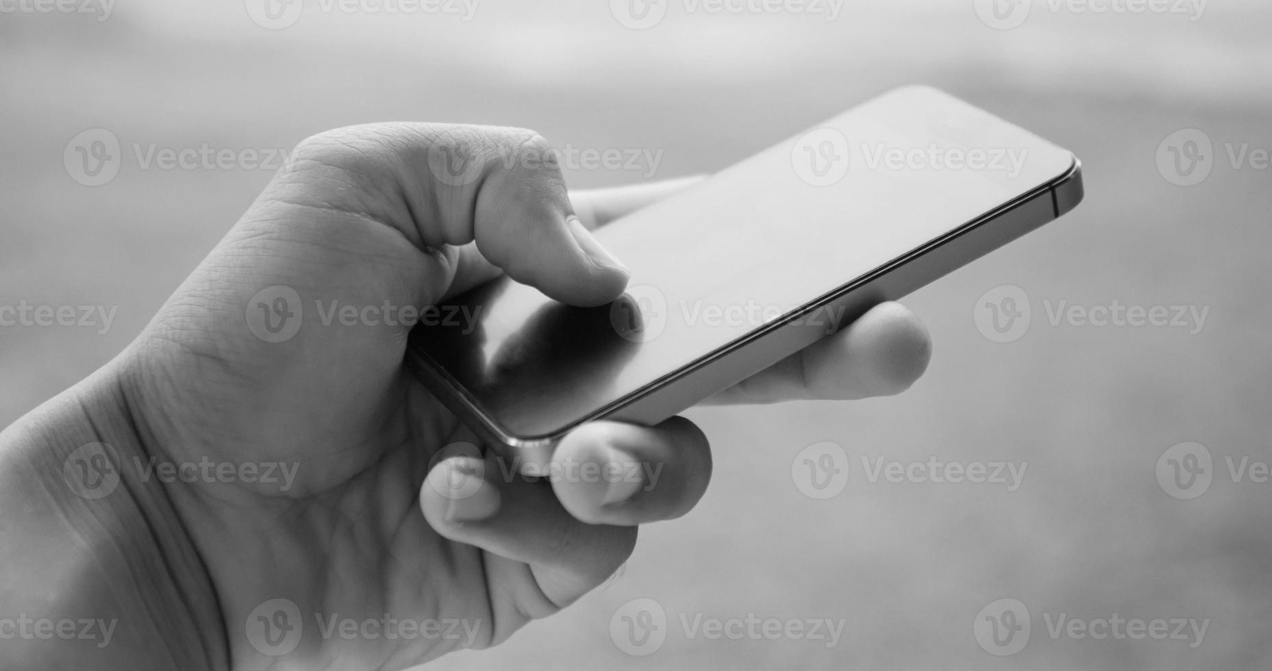 sostenga y toque el teléfono inteligente, imagen en tono blanco y negro foto