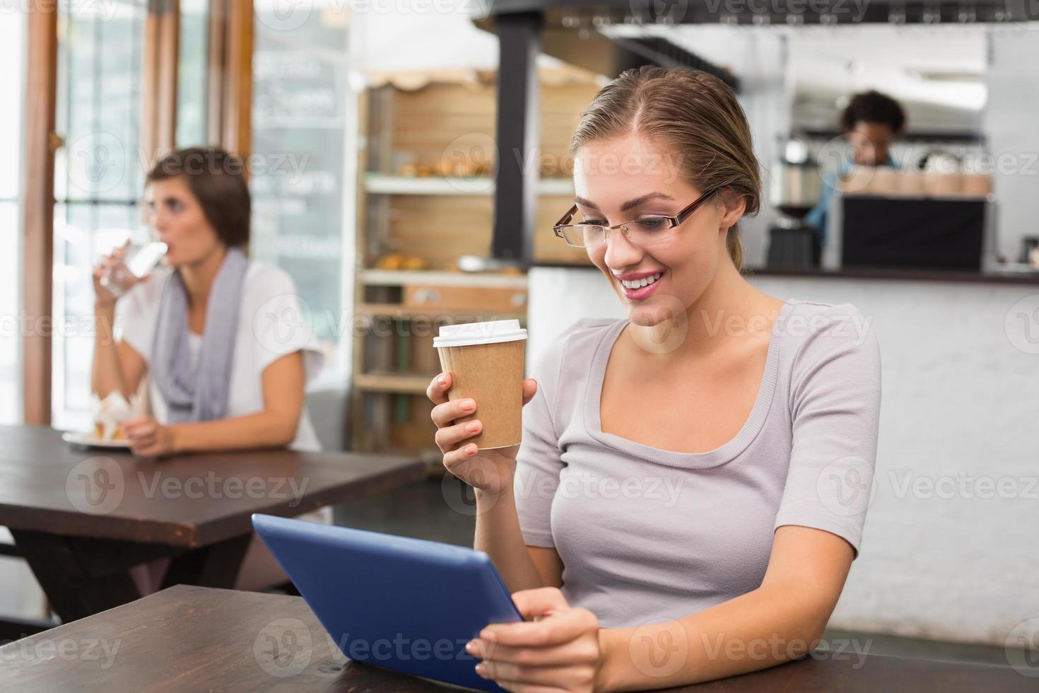 bonita rubia disfrutando de un café con tablet pc foto
