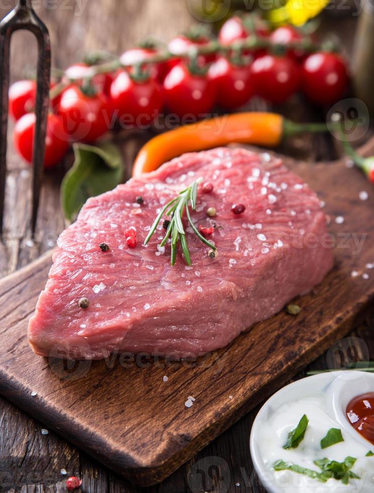 Raw beef steak on wooden table photo