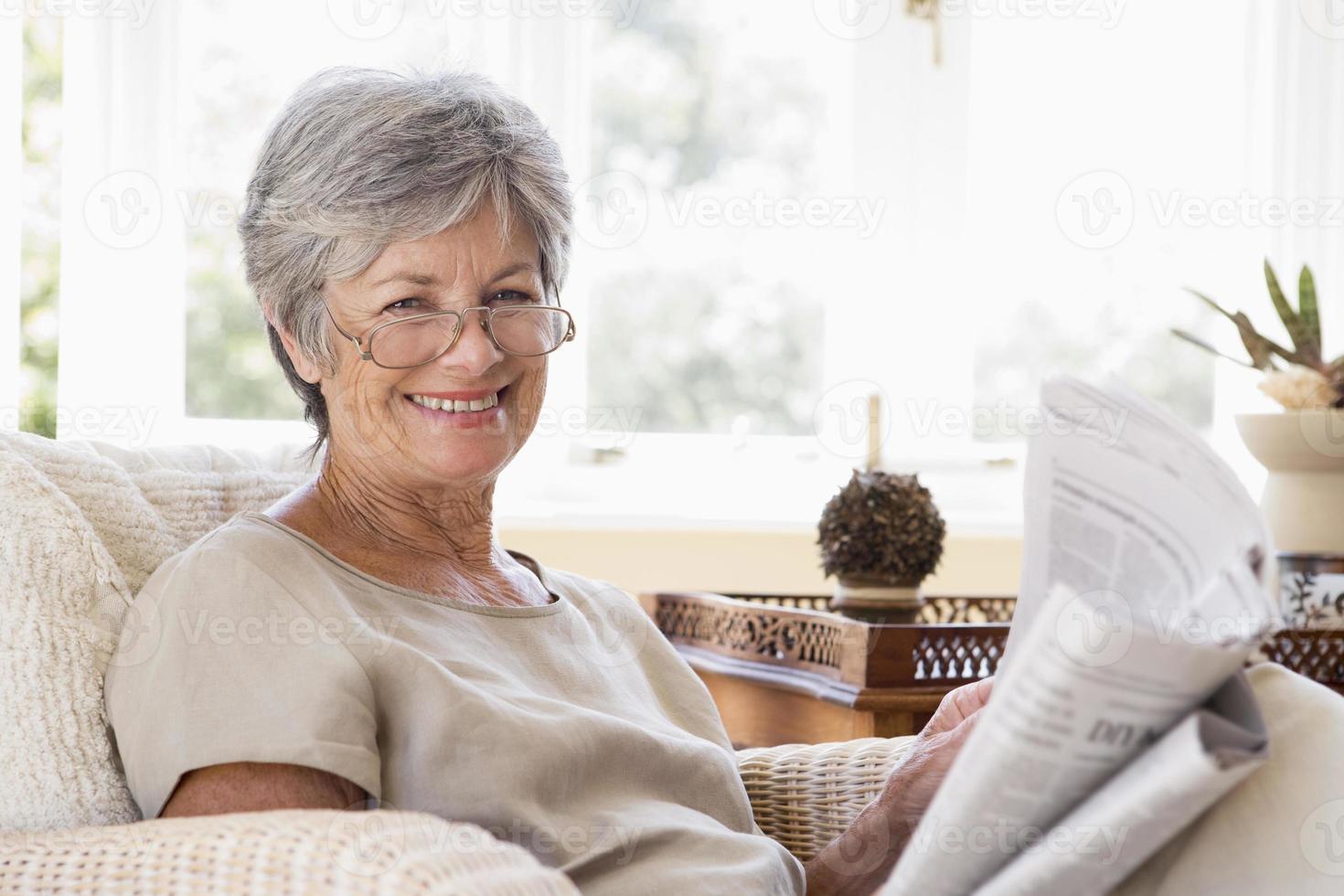 mujer en la sala leyendo el periódico sonriendo foto