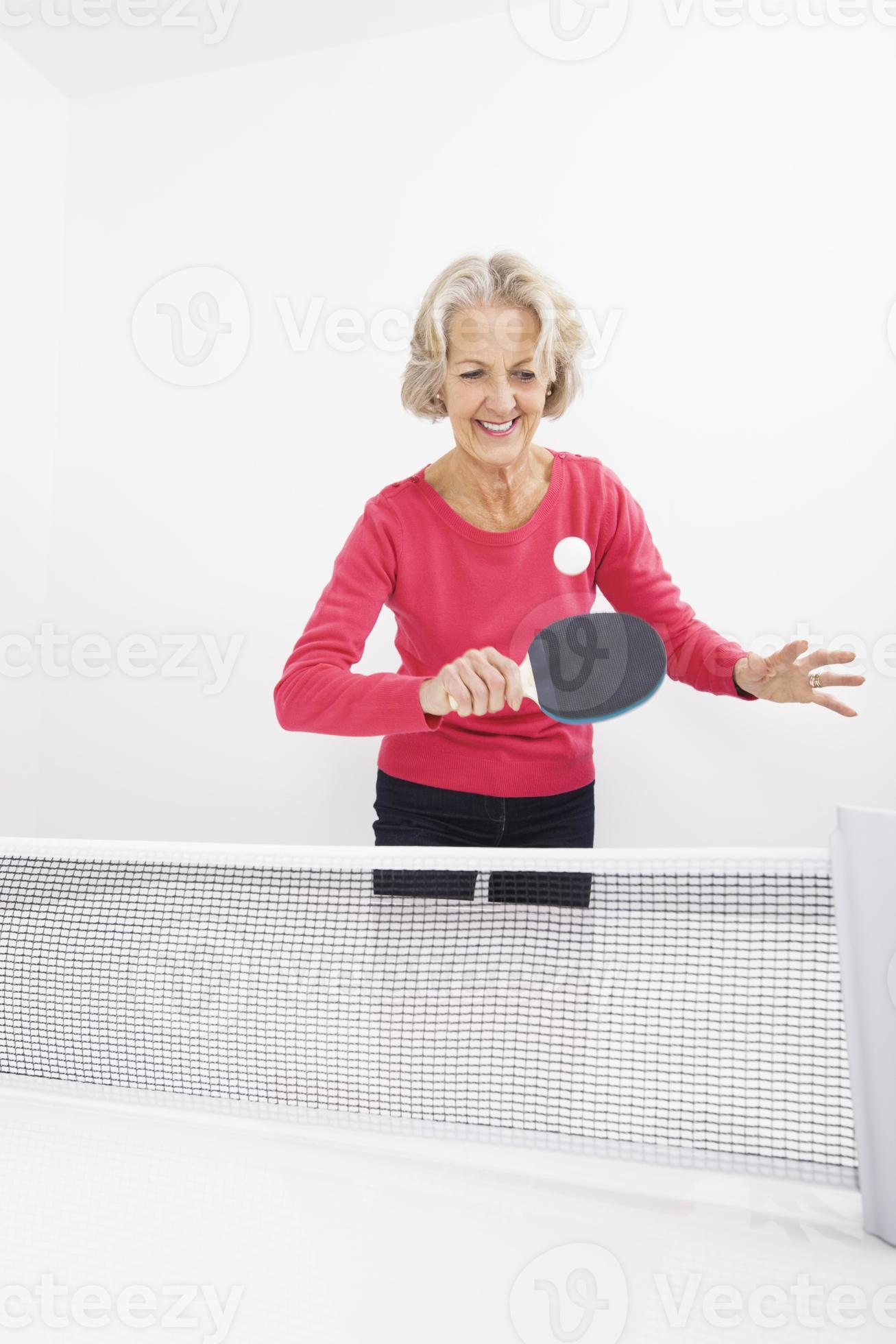 feliz mujer senior jugando tenis de mesa foto