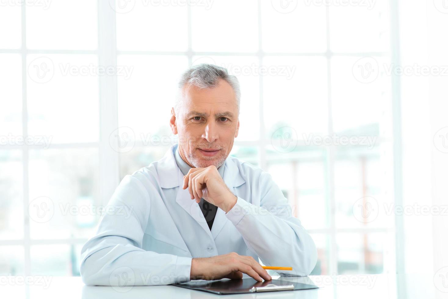 Aged doctor in hospital office photo