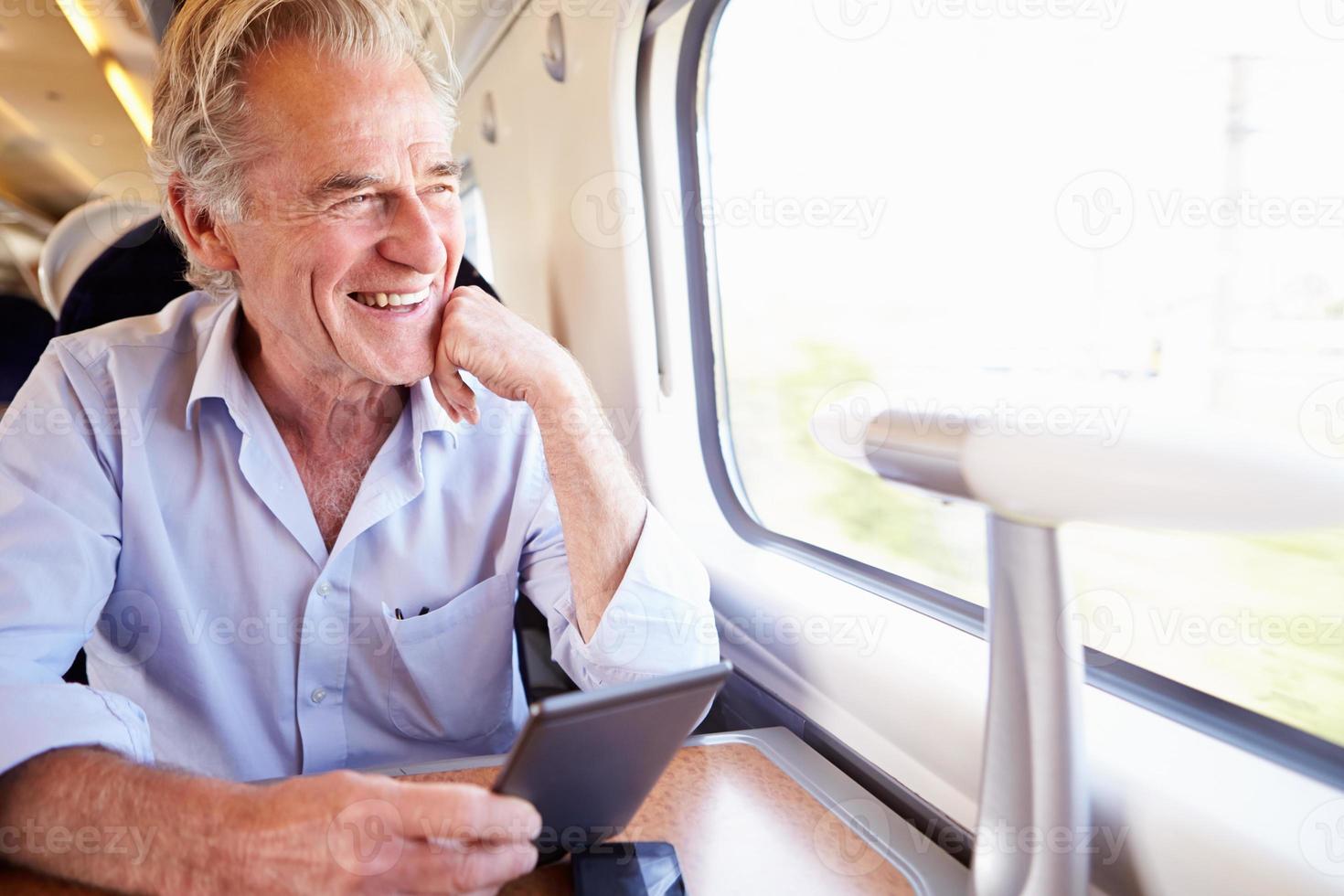 Senior hombre leyendo un libro electrónico en viaje en tren foto