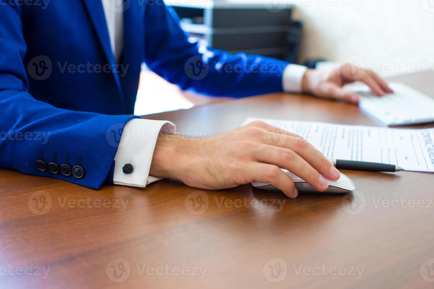 mano masculina que sostiene el ratón de la computadora con el teclado del ordenador portátil foto