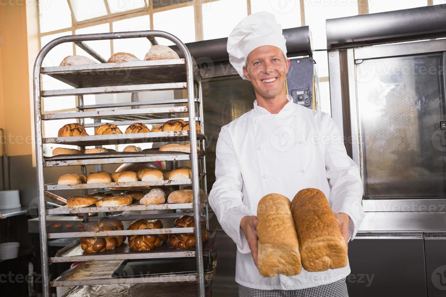 Smiling baker showing loaves of bread photo
