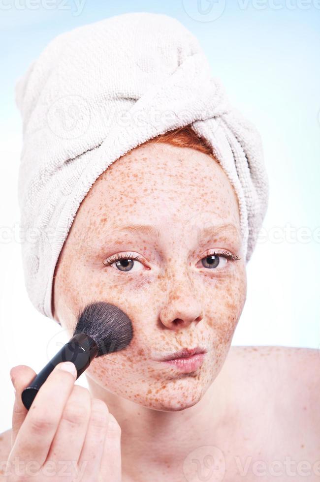 Freckled face girl applying a blush photo