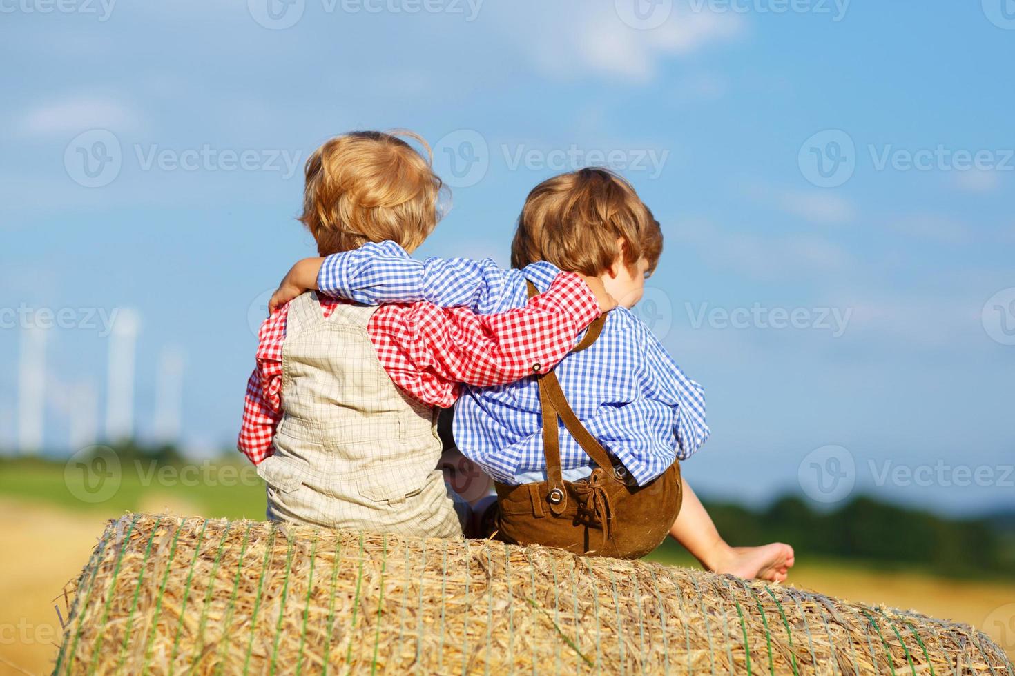 dos niños pequeños y amigos sentados en la pila de heno foto