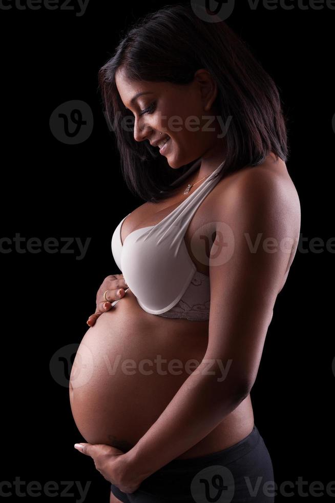 Young beautiful pregnant indian woman touching her tummy photo