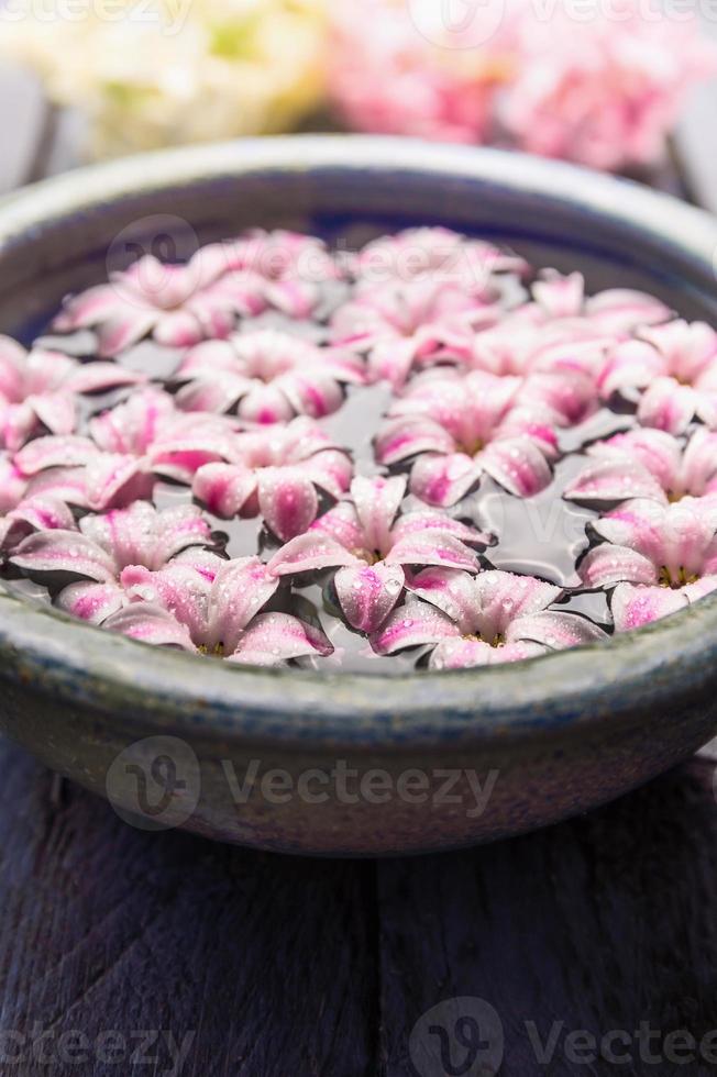 Pink roses petals in bowl with towels and pure water over white