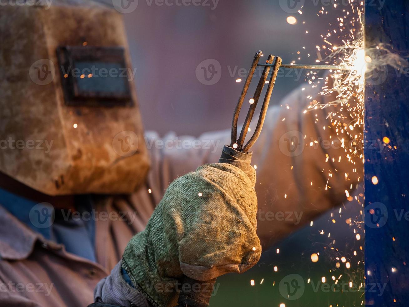 Arc welder worker in protective mask welding metal construction photo
