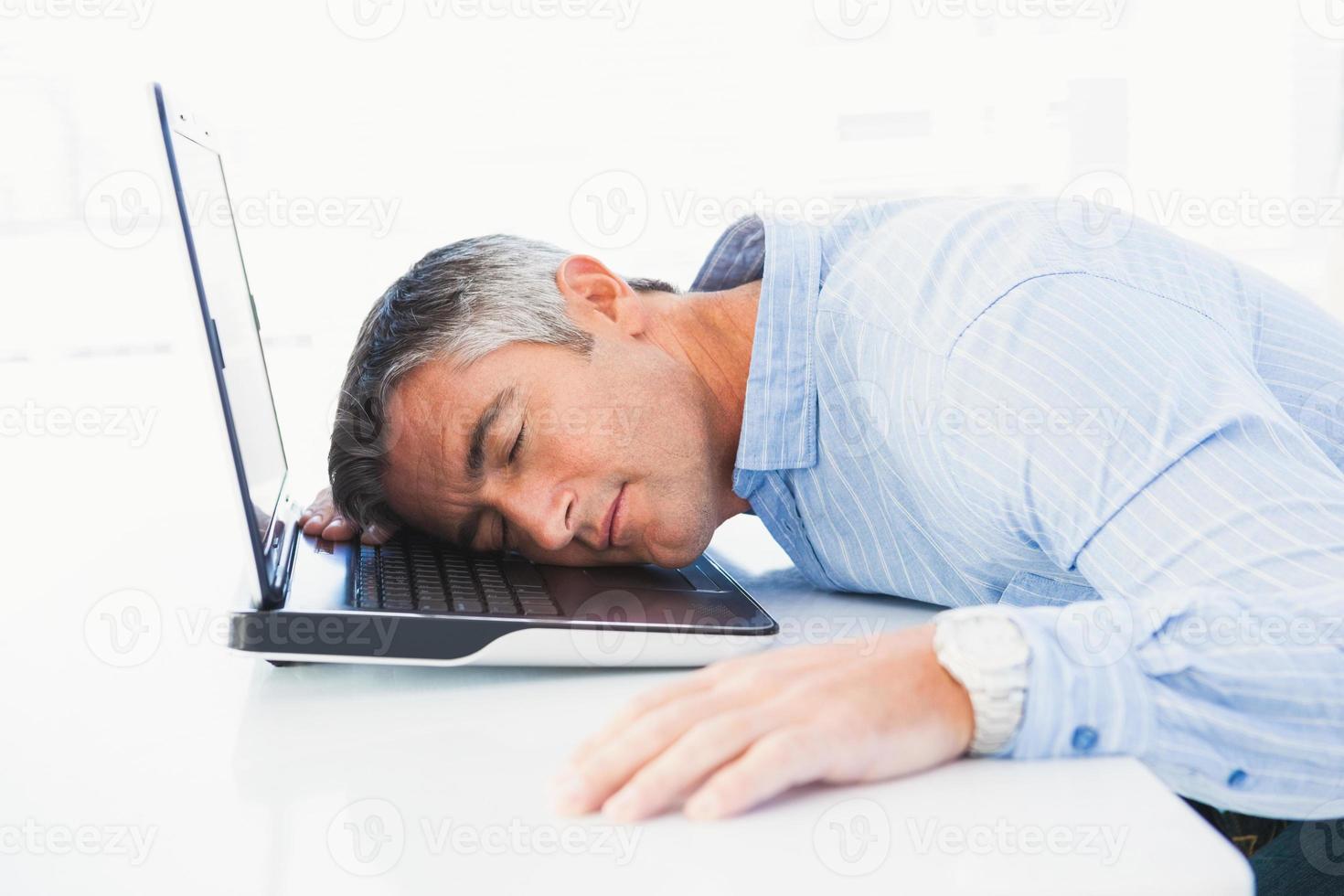 hombre con canas durmiendo en su computadora portátil foto