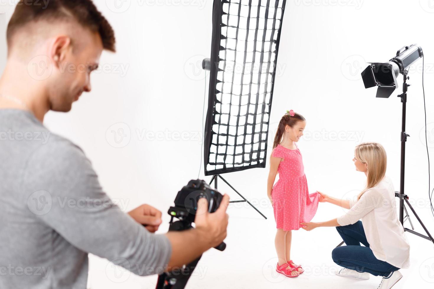 Photographer checks his camera while model is being prepared photo