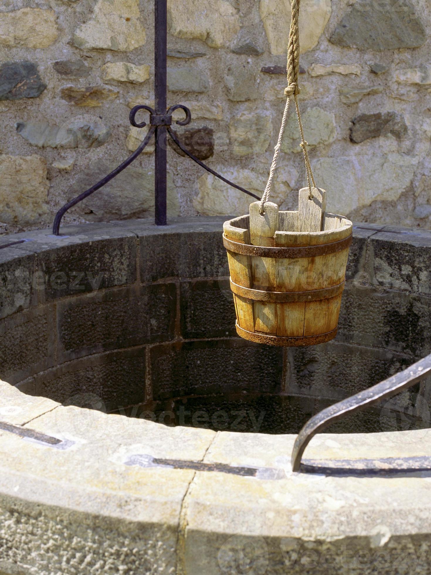 Wishing well with a bucket ready to be lowered by a rope 874552 Stock