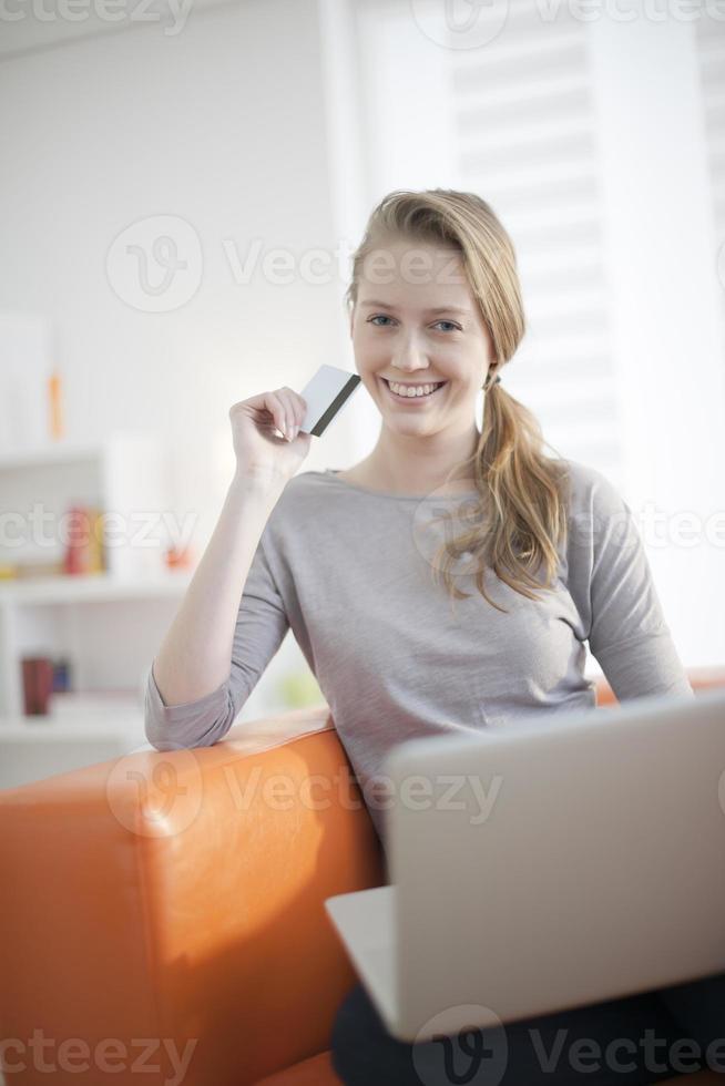 young woman sitting on her couch with his computer photo