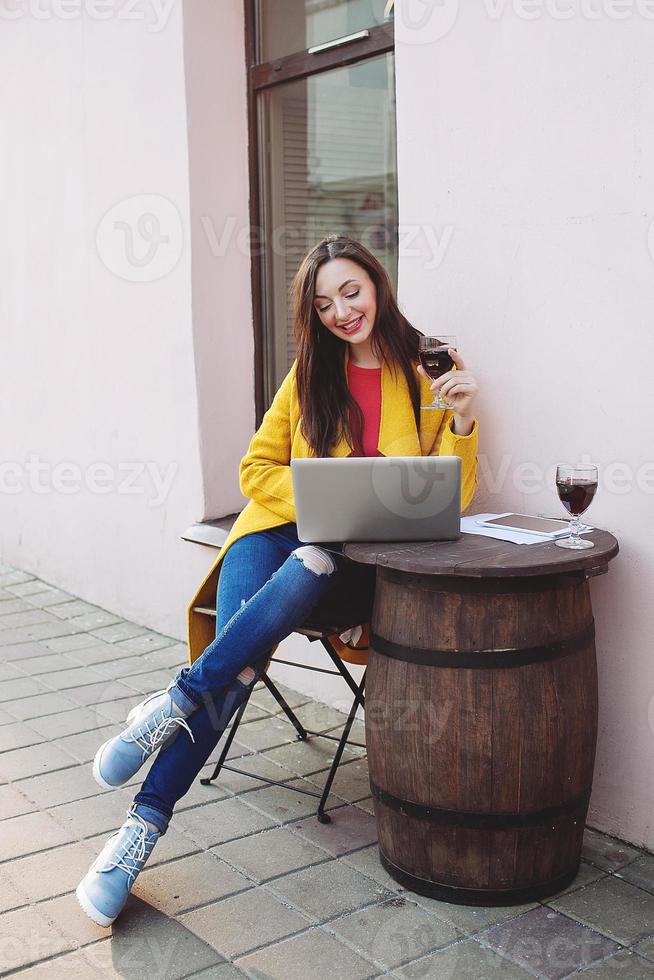 Mujer con tableta de vino tinto y portátil en street cafe foto