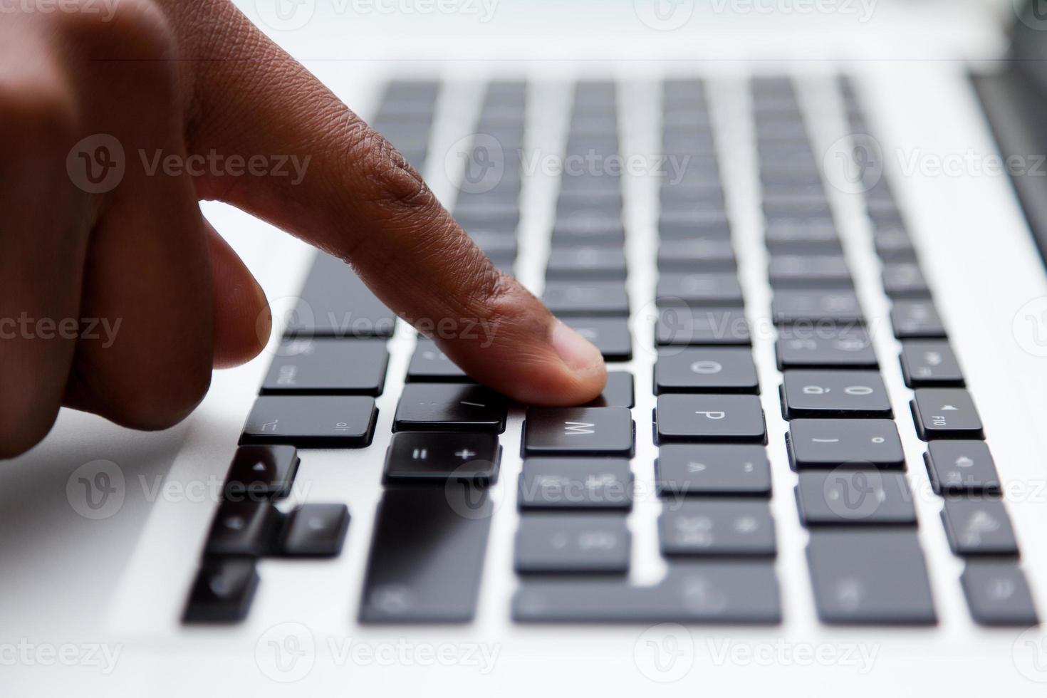 Make finger pressing letter on black keyboard photo