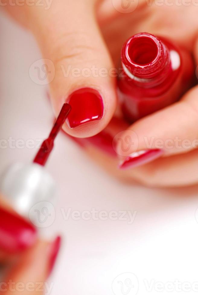 mujer aplicando esmalte de uñas rojo foto