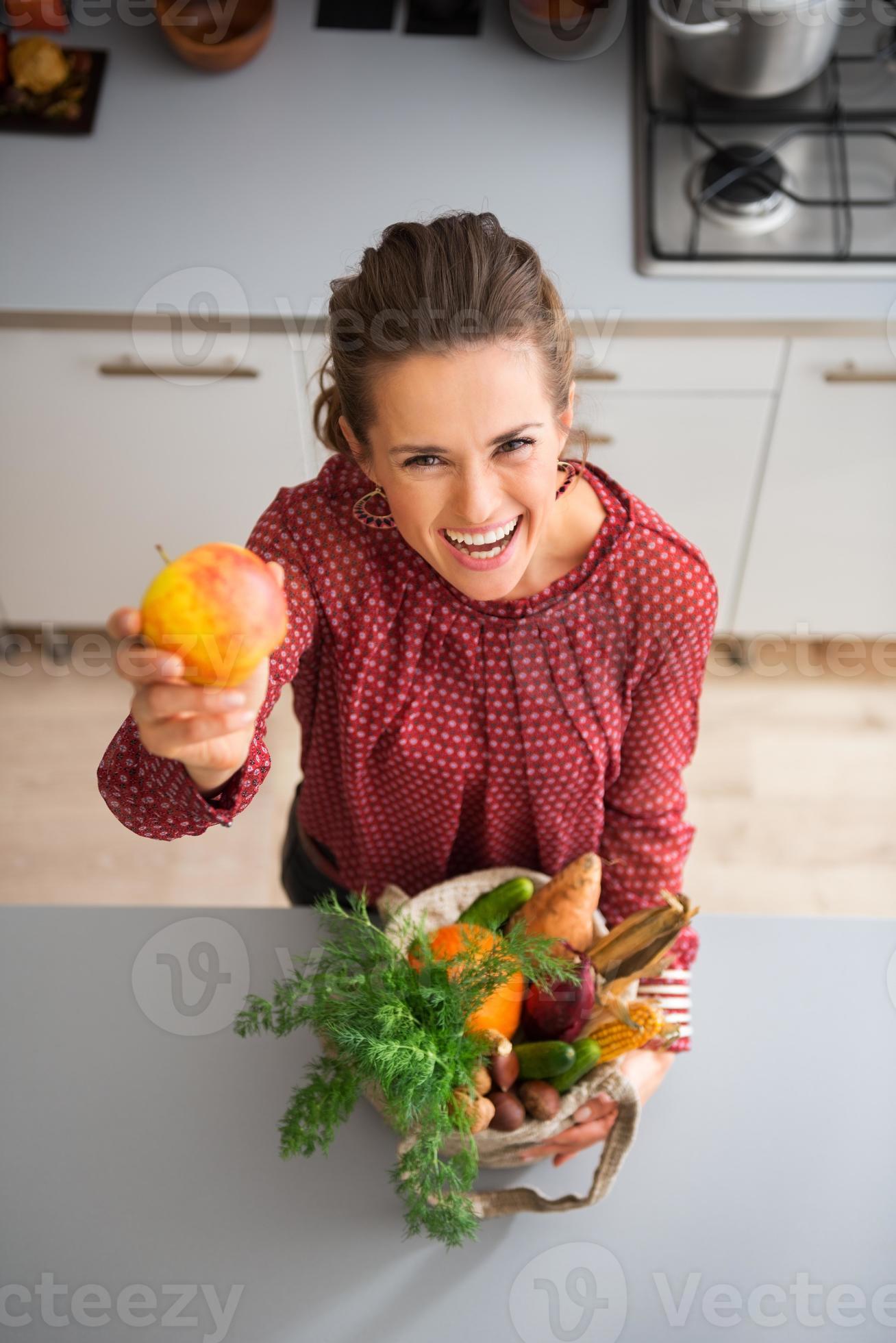 mujer feliz sosteniendo una manzana en la cocina foto