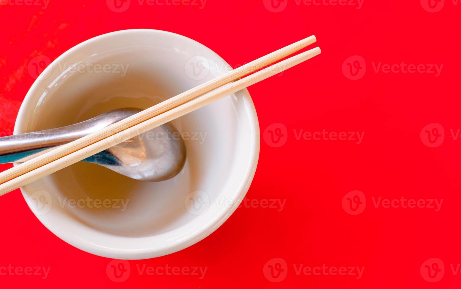 tazón de arroz y cuchara y palillos en la mesa roja foto