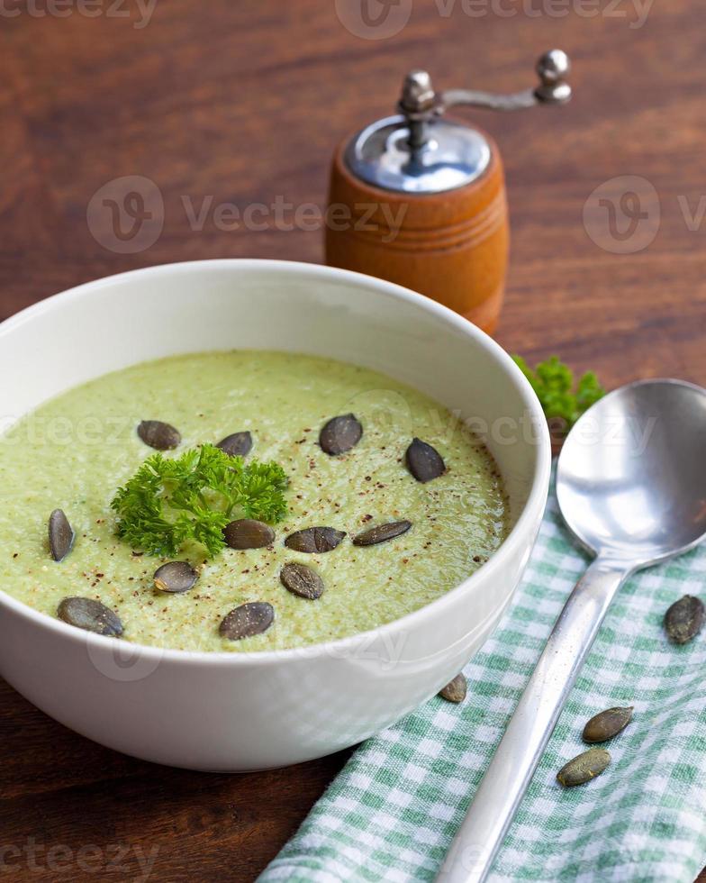 Homemade green broccoli cream soup served in white bowl photo