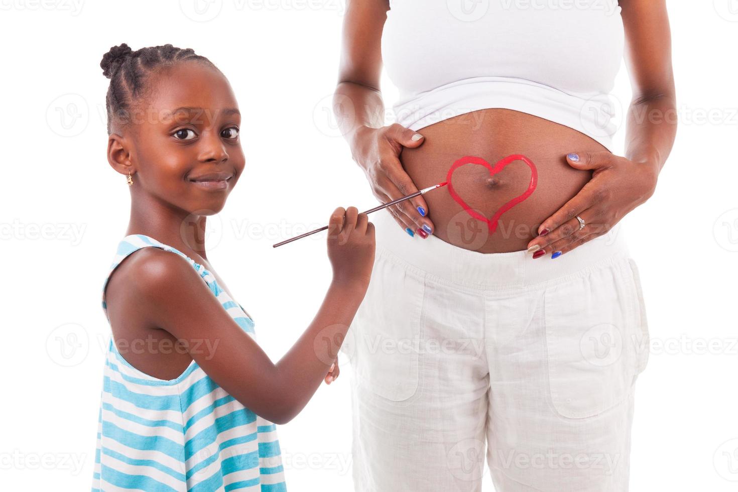 Little african american girl painting on her mother's belly photo
