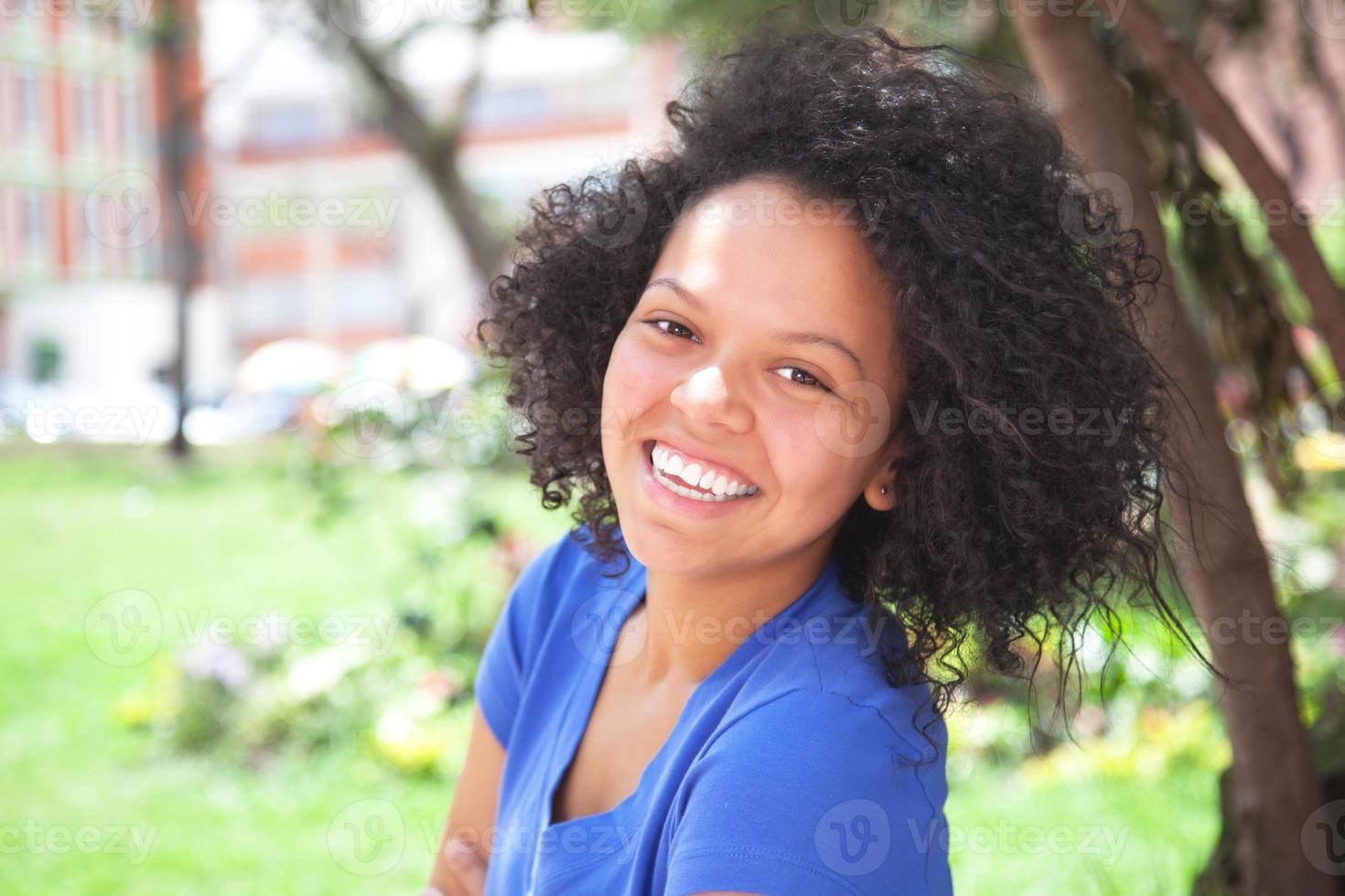 niña caribeña en camisa azul riéndose de la cámara foto