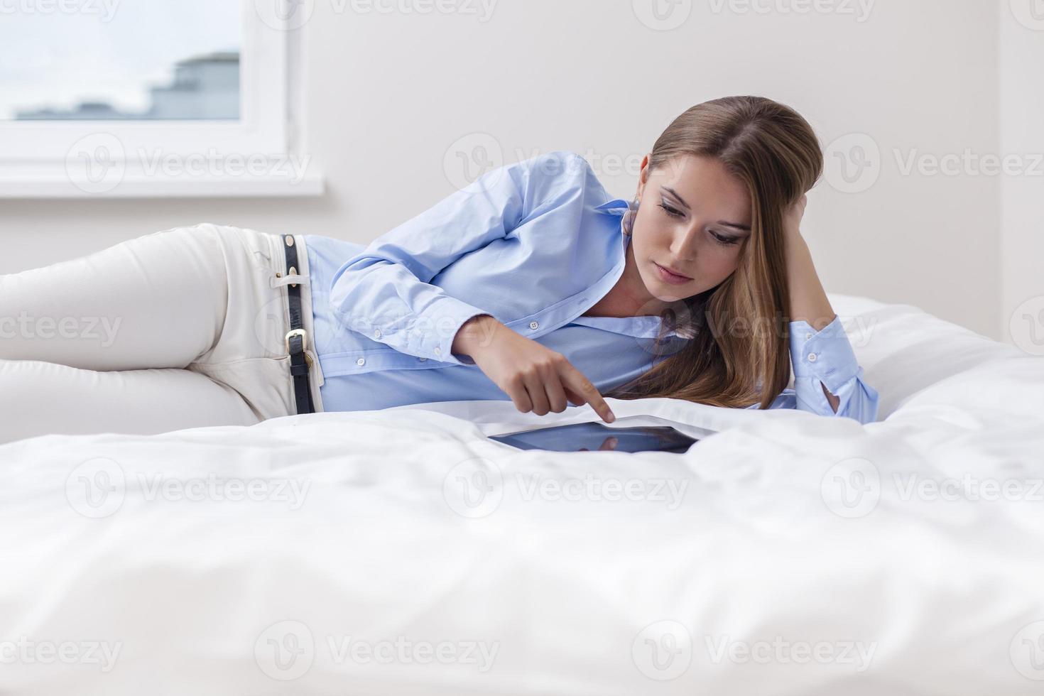 hermosa mujer usando tableta en su cama foto