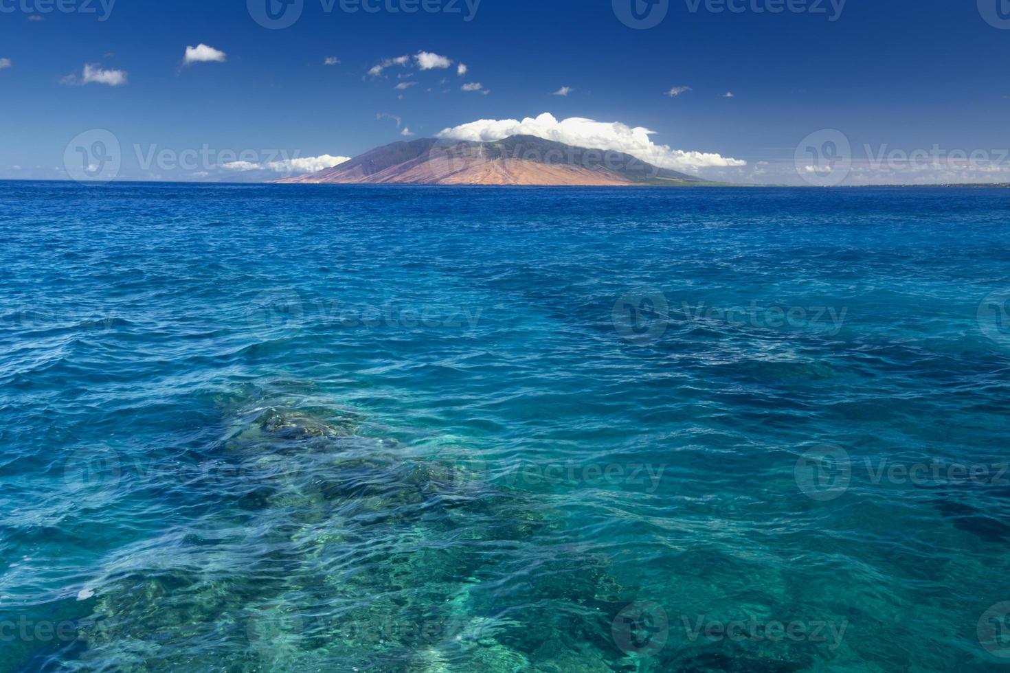 arrecife en agua clara con las montañas del oeste de maui, hawaii, estados unidos foto