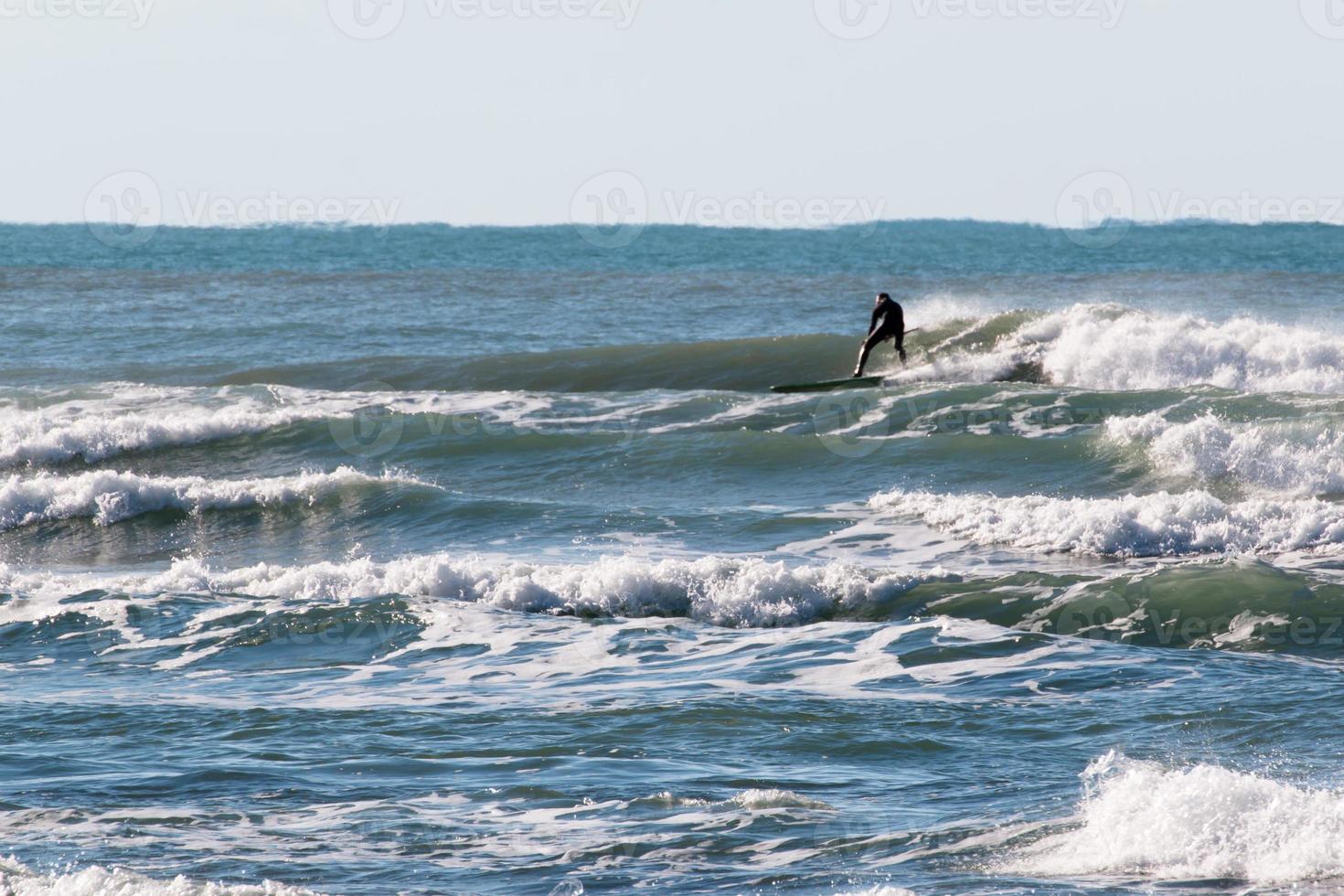 traje de surfista negro montando la ola foto