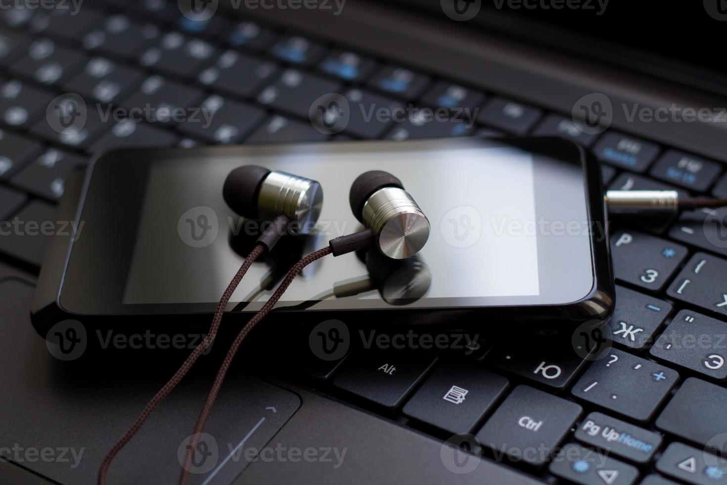 Headphones and  cell phone at the keyboard. photo