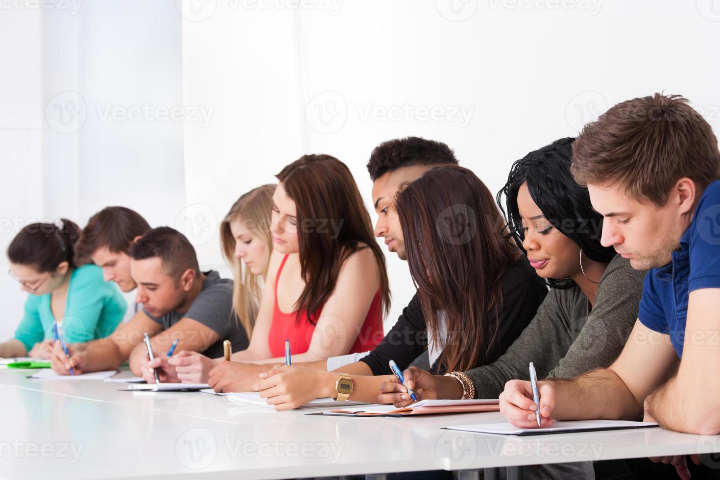 fila de estudiantes universitarios escribiendo en el escritorio foto