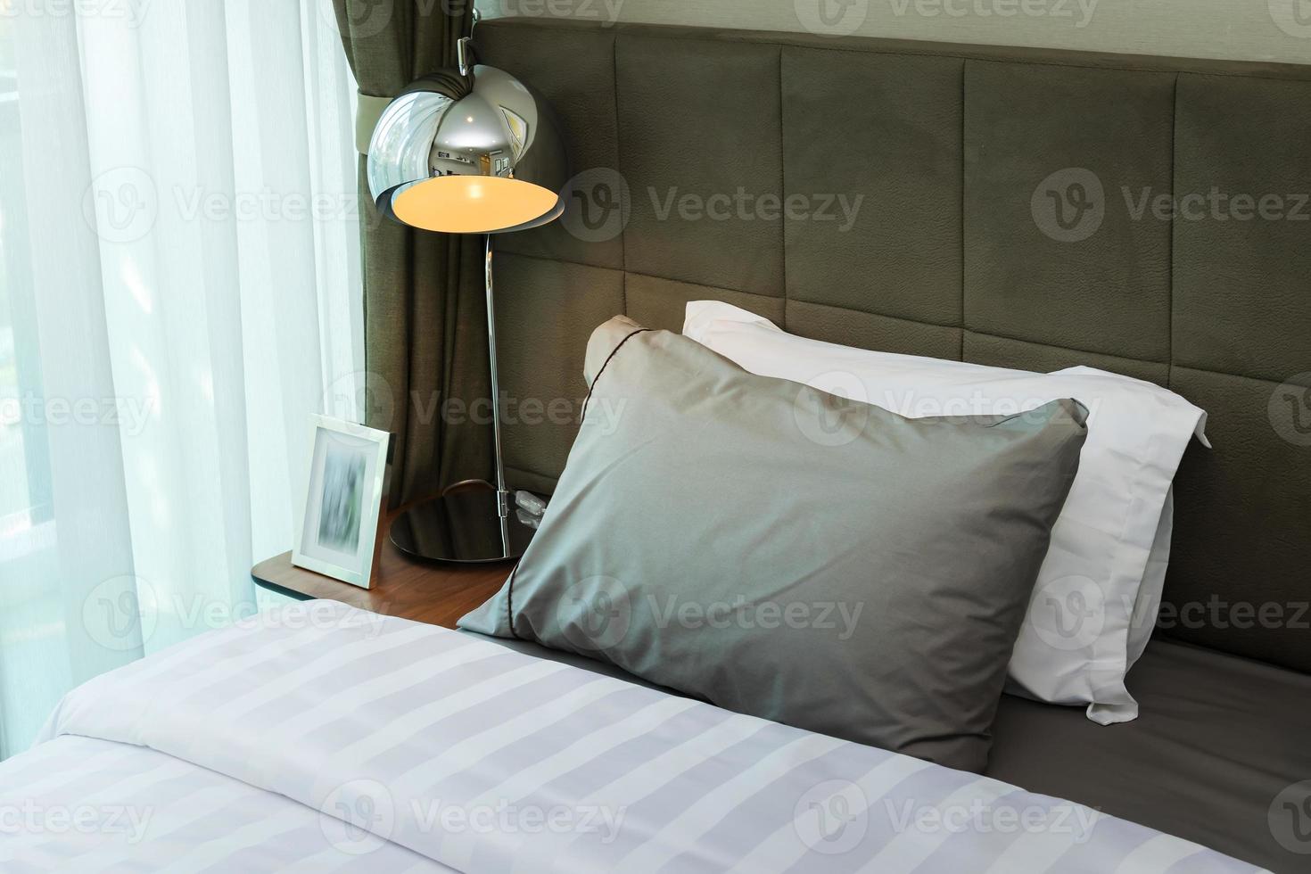 metal desk lamp and grey pillow on bed photo