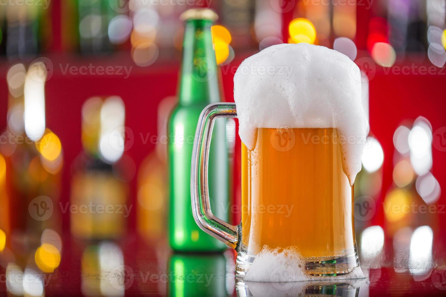 Botella de cerveza con vaso en la barra de escritorio foto