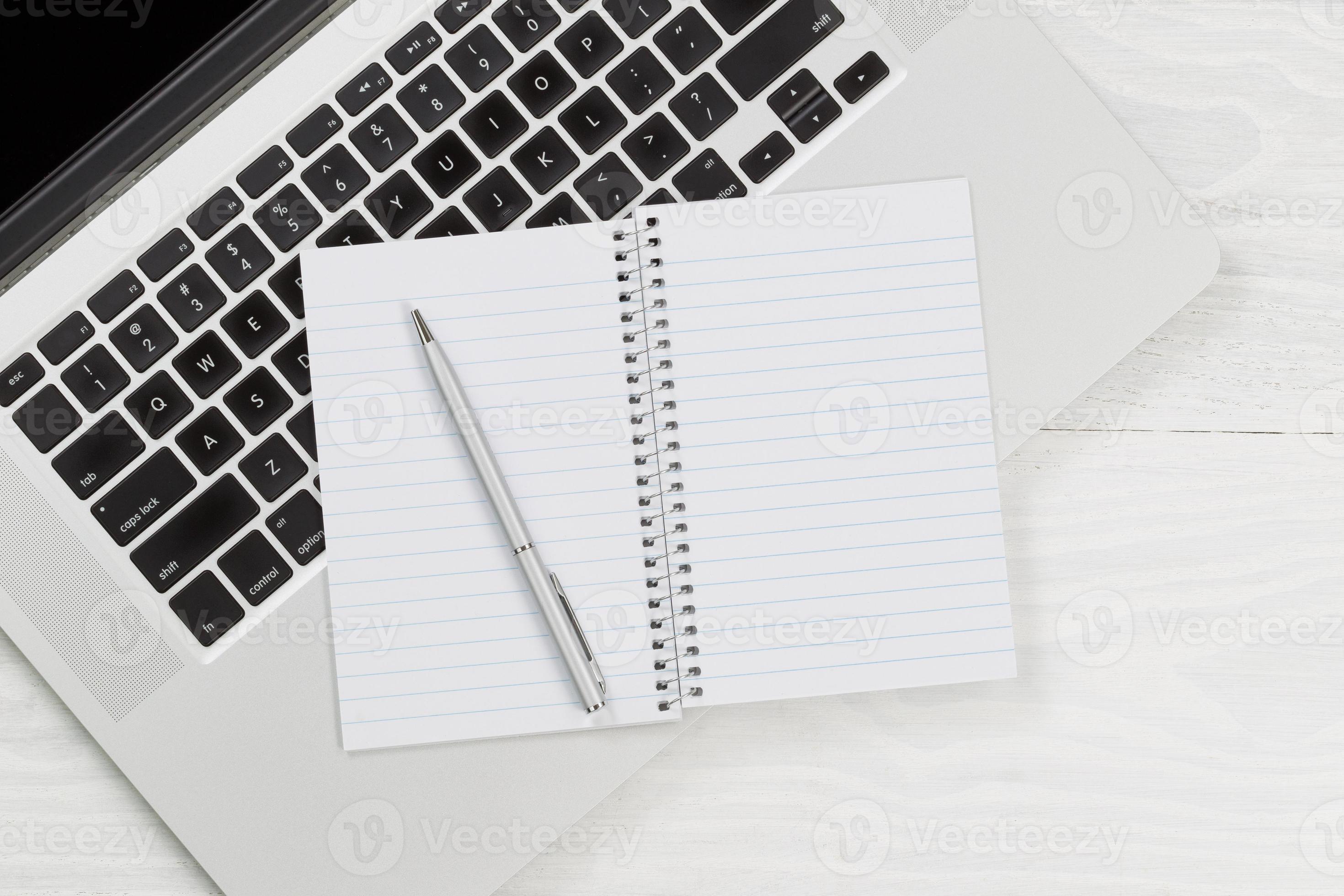 Laptop computer with blank notepad and pen on white desktop 893941