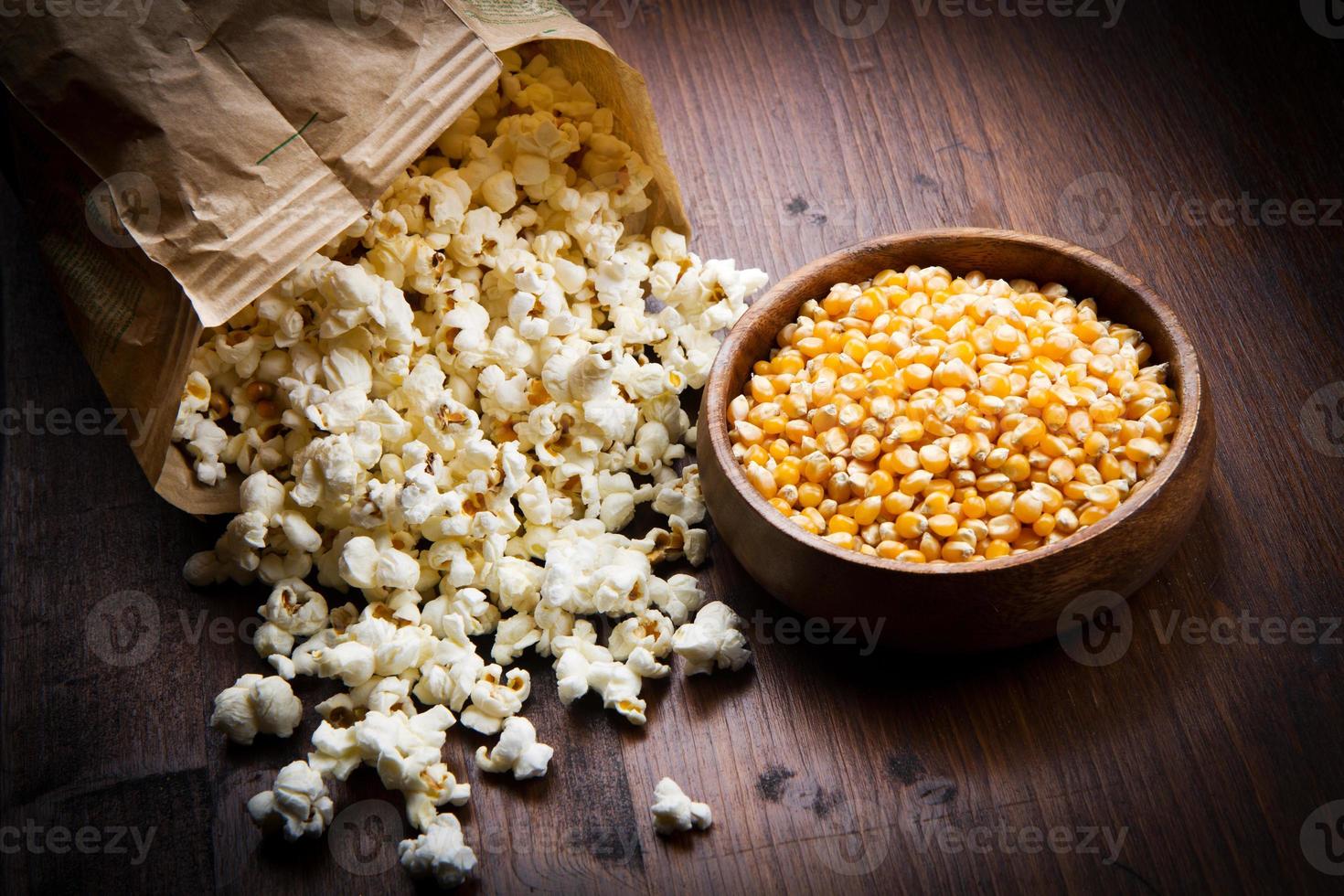 bowl of popcorn and kernelson a wooden table photo