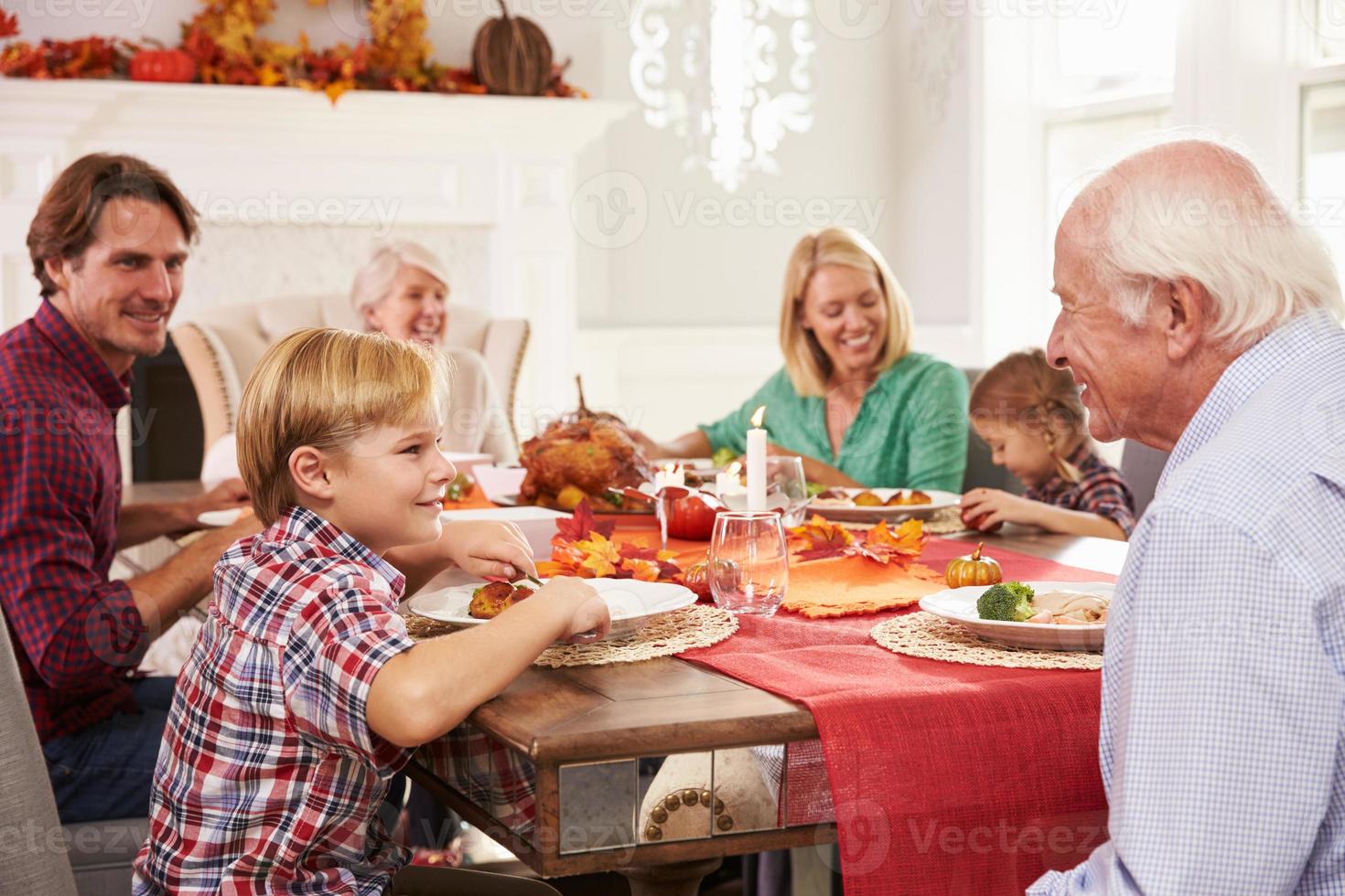 familia con abuelos disfrutando de comida de acción de gracias en la mesa foto