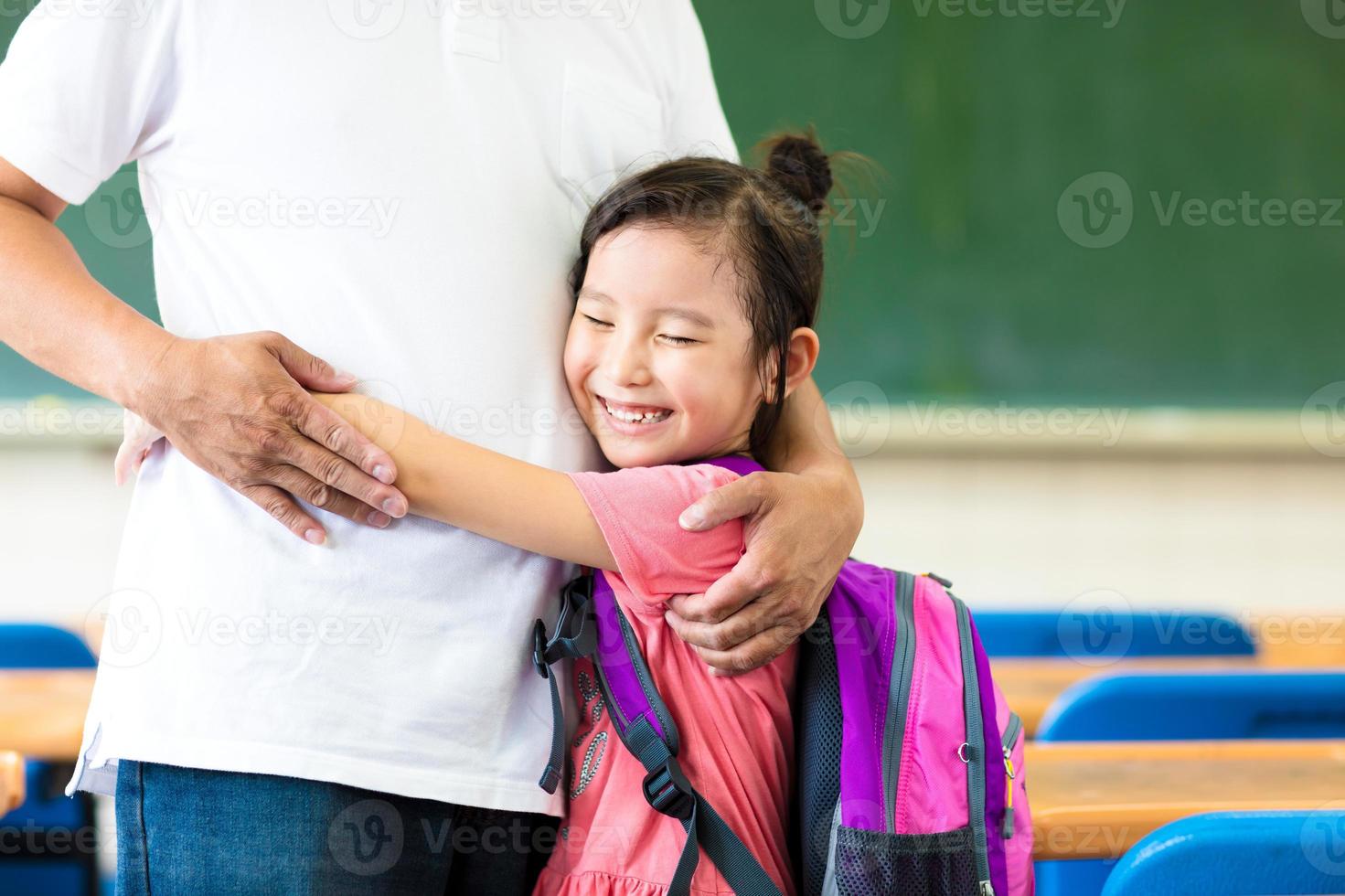 niña feliz abrazando a su padre en el aula foto