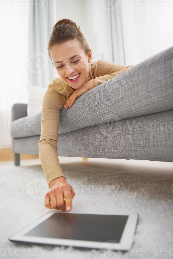 mujer joven feliz con tablet pc mientras está acostado en el sofá foto
