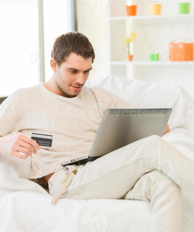 young man with laptop and credit card at home photo