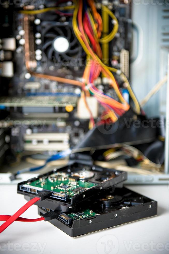 Dos discos duros y cables rojos con placa base en segundo plano. foto