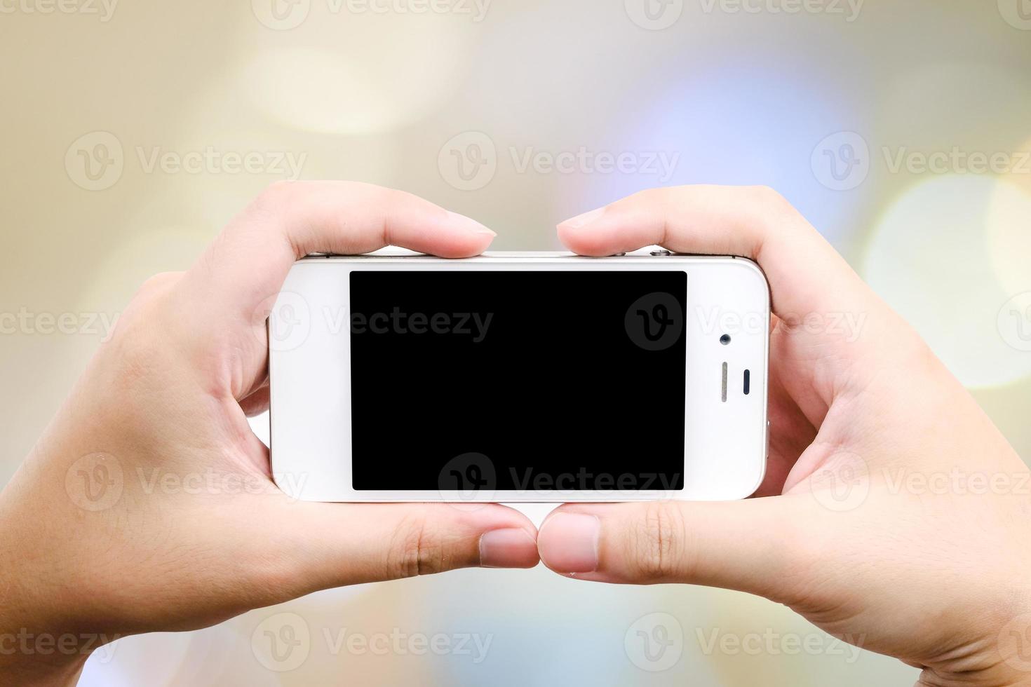Teléfono inteligente en mano sobre fondo bokeh foto