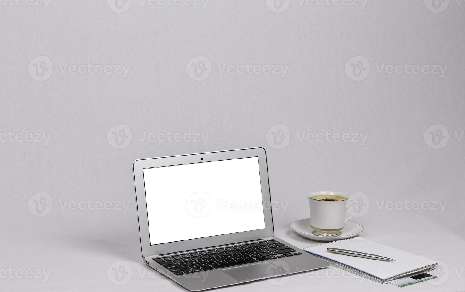 portátil blanco con taza de bolígrafo plateado capuchino en la mesa foto