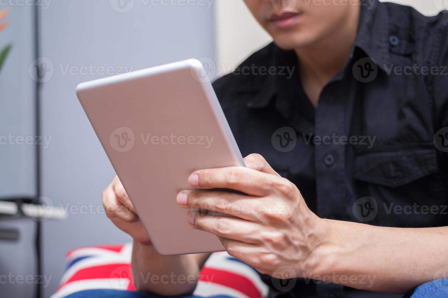 hombre asiático en camisa negra juega su tableta foto