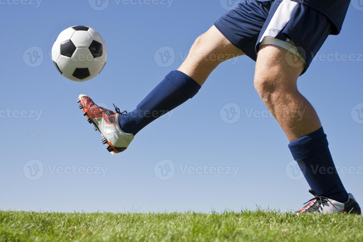 Soccer player and green grass kicking a soccer ball up 897391 Stock