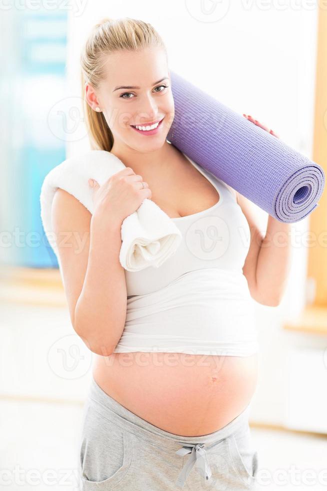 Pregnant woman holding yoga mat photo