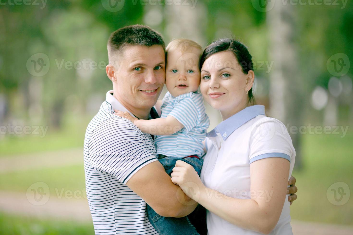 feliz familia joven mamá papá y bebé en el parque foto