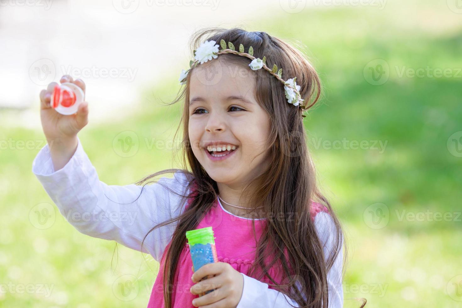 Beautiful portrait of sweet lovely little girl blowing soap bubb photo