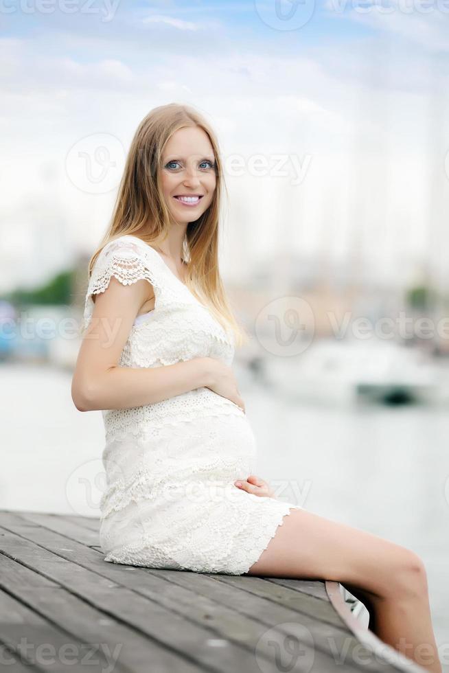embarazo mujer sentada en el puerto de mar foto