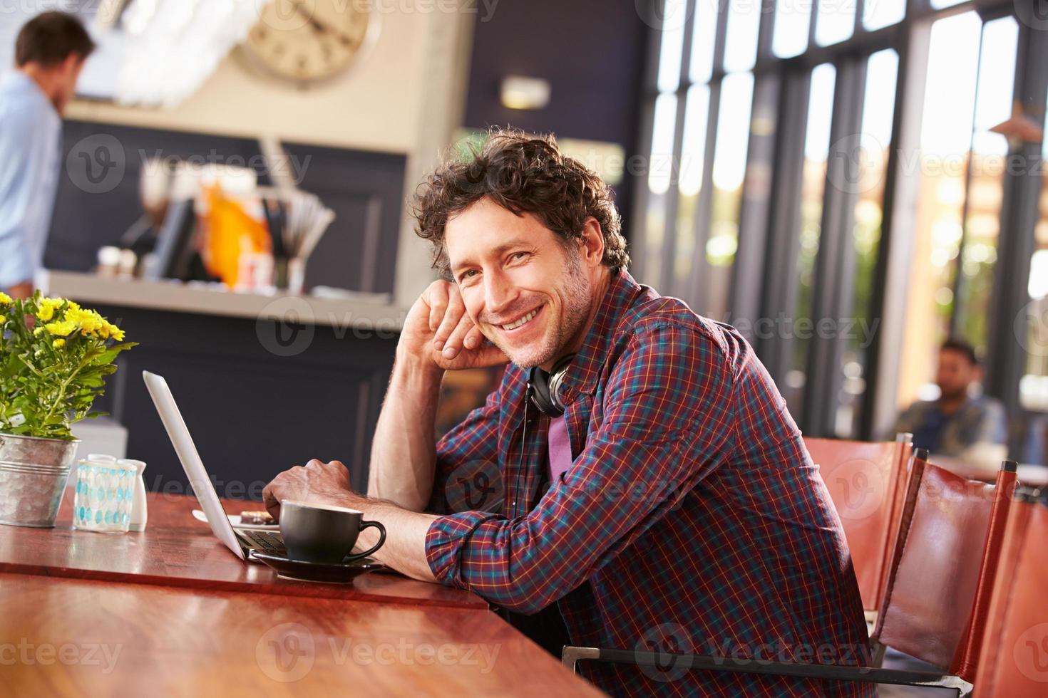 hombre trabajando en la computadora en la cafetería, retrato foto