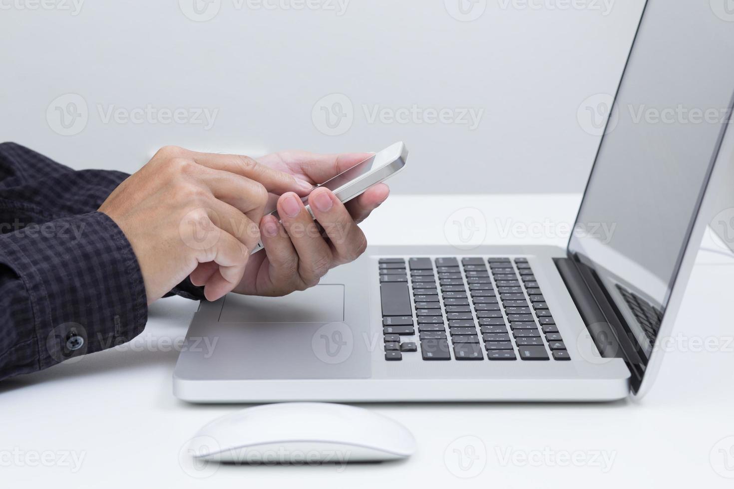 Man hands holding smart phone with laptop computer background photo